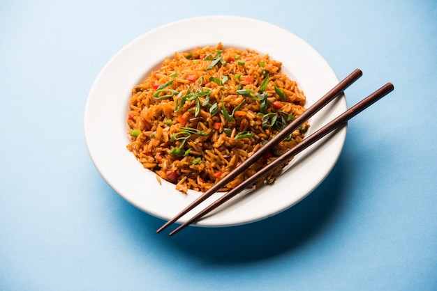 Schezwan Fried Rice Masala é uma comida indo-chinesa popular servida em um prato ou tigela com pauzinhos. foco seletivo