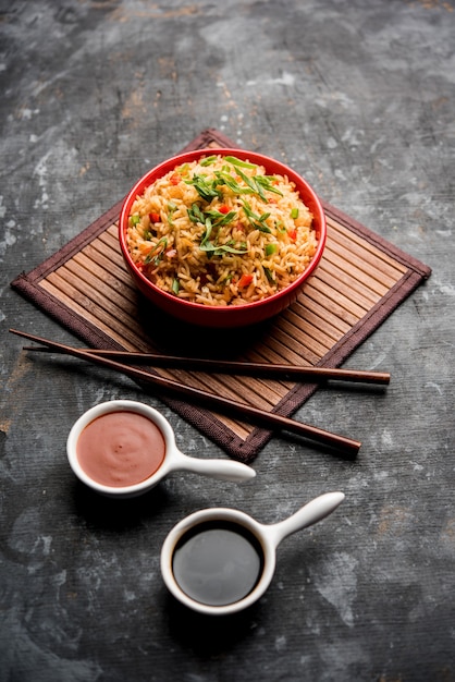 Schezwan Fried Rice Masala ist ein beliebtes indochinesisches Essen, das in einem Teller oder einer Schüssel mit Stäbchen serviert wird. selektiver Fokus