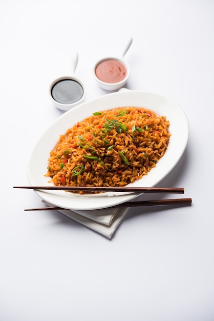 Schezwan Fried Rice Masala ist ein beliebtes indochinesisches Essen, das in einem Teller oder einer Schüssel mit Stäbchen serviert wird