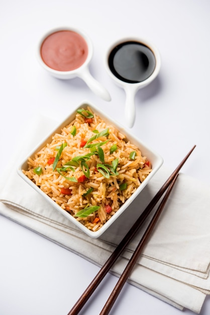 Schezwan Fried Rice Masala ist ein beliebtes indochinesisches Essen, das in einem Teller oder einer Schüssel mit Stäbchen serviert wird