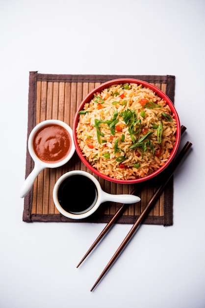 Schezwan Fried Rice Masala ist ein beliebtes indochinesisches Essen, das in einem Teller oder einer Schüssel mit Stäbchen serviert wird