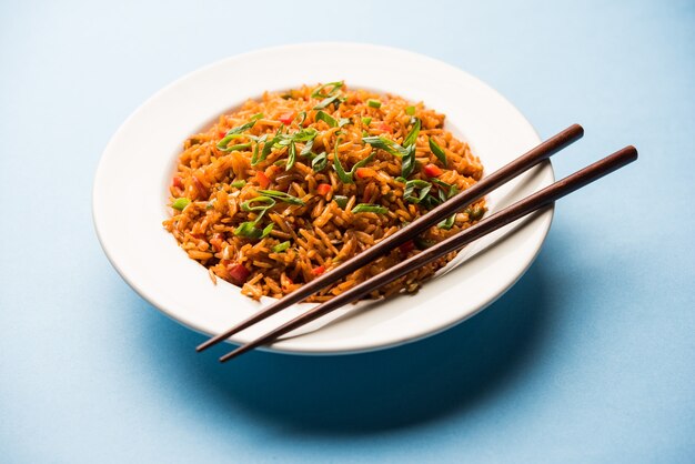 Schezwan Fried Rice Masala ist ein beliebtes indochinesisches Essen, das in einem Teller oder einer Schüssel mit Stäbchen serviert wird