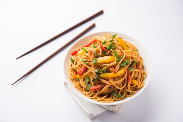 Schezwan-Nudeln oder Gemüse-Hakka-Nudeln oder Chow Mein ist ein beliebtes indo-chinesisches Rezept, das in einer Schüssel oder auf einem Teller mit Holzstäbchen serviert wird. selektiver Fokus