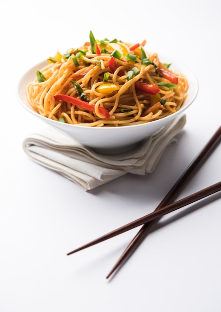 Schezwan-Nudeln oder Gemüse-Hakka-Nudeln oder Chow Mein ist ein beliebtes indo-chinesisches Rezept, das in einer Schüssel oder auf einem Teller mit Holzstäbchen serviert wird. selektiver Fokus