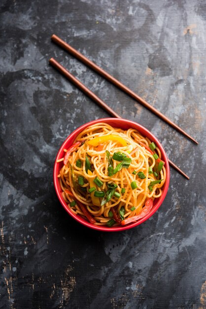 Schezwan-Nudeln oder Gemüse-Hakka-Nudeln oder Chow Mein ist ein beliebtes indo-chinesisches Rezept, das in einer Schüssel oder auf einem Teller mit Holzstäbchen serviert wird. selektiver Fokus