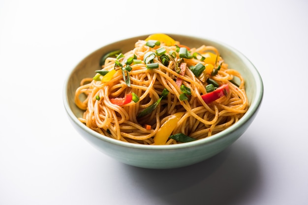 Schezwan-Nudeln oder Gemüse-Hakka-Nudeln oder Chow Mein ist ein beliebtes indo-chinesisches Rezept, das in einer Schüssel oder auf einem Teller mit Holzstäbchen serviert wird. selektiver Fokus