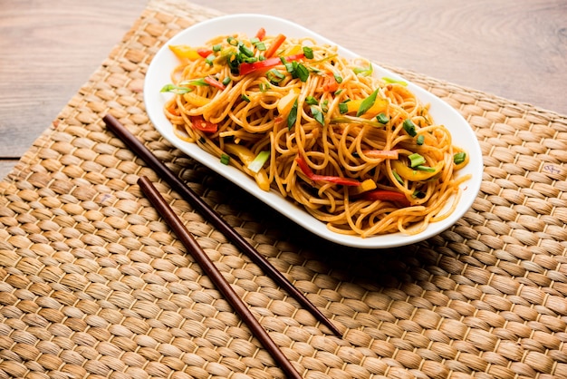 Schezwan-Nudeln oder Gemüse-Hakka-Nudeln oder Chow Mein ist ein beliebtes indo-chinesisches Rezept, serviert in einer Schüssel oder einem Teller mit Holzstäbchen