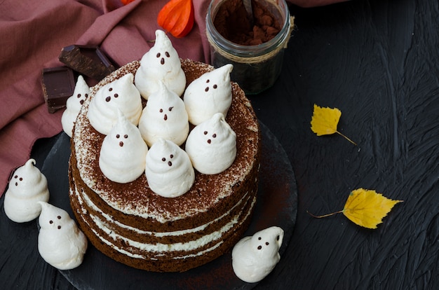 Schichtet Schokoladenkuchen mit weißer Schokoladencreme und Baisergeistern darauf