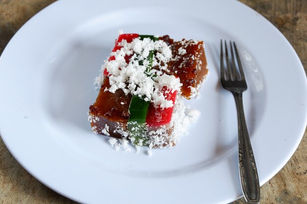 Schichtkuchen und Kokosraspeln auf Teller mit Besteck, malaiisches Essen