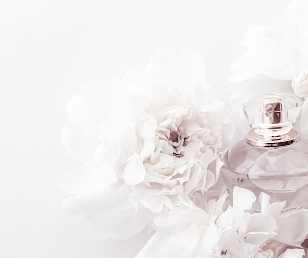 Schicke Duftflasche als luxuriöses Parfümprodukt auf dem Hintergrund von Pfingstrosenblumen, Parfümwerbung und Beauty-Branding