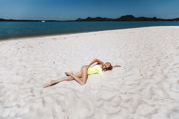 Schicke erwachsene Dame mit attraktiver sexy Figur und langen Beinen, die an einem heißen Sommertag im Sand eines örtlichen Strandes liegt und sich sonnen. Urlaubskonzept.
