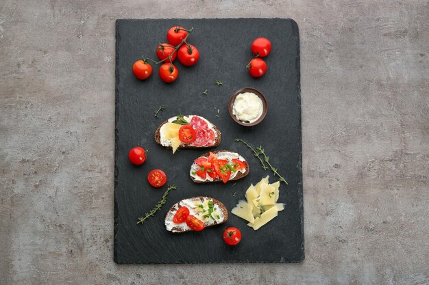 Schieferplatte mit köstlichen Bruschettas auf grauem Hintergrund