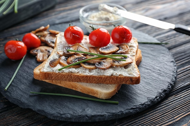 Schieferplatte mit leckerem Toast, Käse und Gemüse auf dem Tisch