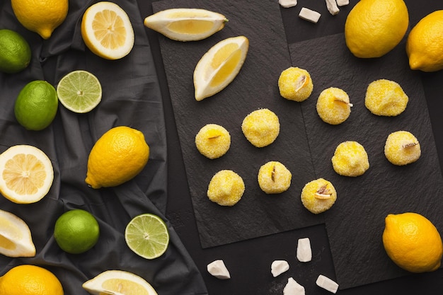 Schieferplatten mit einer Auswahl an Zitronen und Limetten auf schwarzem Hintergrund, Kopierraum. Draufsicht auf reife exotische Früchte und Rahat Lakoum, flache Lage