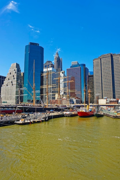 Schiffe im Hafen von South Street Seaport am East River. Lower Manhattan in New York, USA, ist im Hintergrund. Pier 17. Touristen herum.