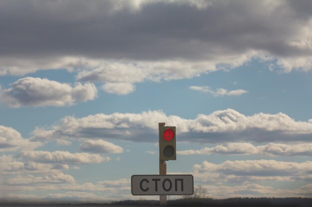 Schild STOP und Ampel mit Rot gegen Wolken und Himmel, Tele