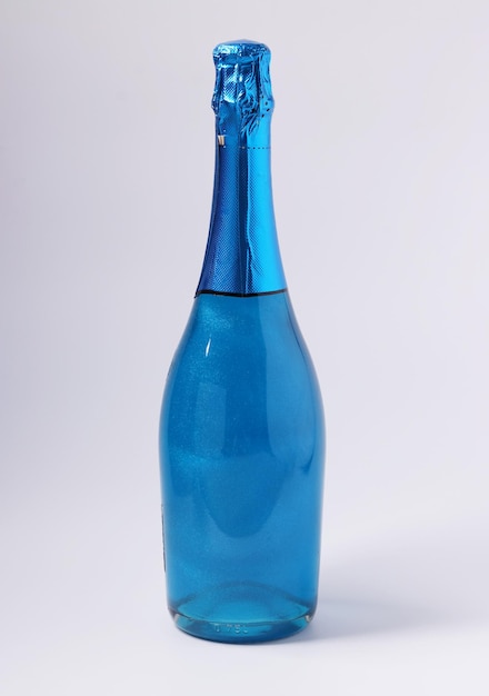 Schimmer essbarer Glitzer funkelnder blauer Champagner in Flasche auf weißem Hintergrund Hochformat