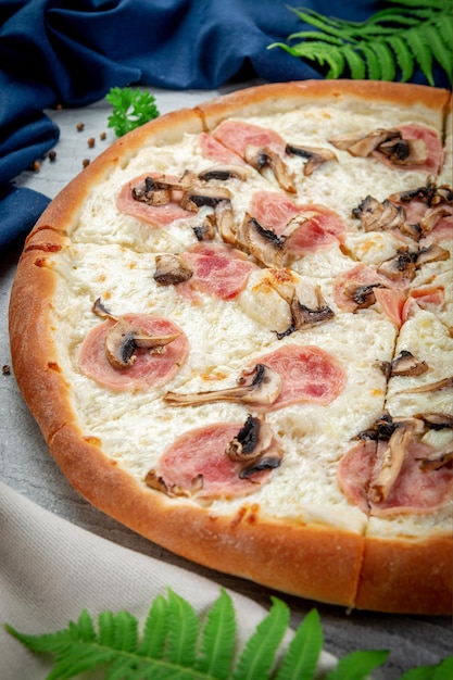 Schinken-Pilz-Pizza auf einem Pfannenwender Frisch gebacken mit Parmesan-Sahne-Sauce Schinken und Champignons