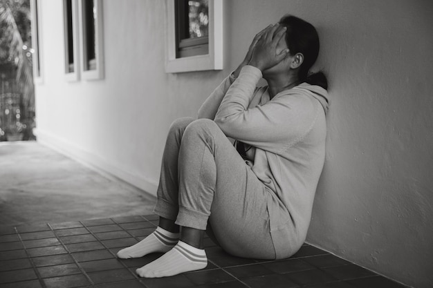 Schizophrenie mit einsamem und traurigem Depressionskonzept für psychische Gesundheit Depressive Frau, die zu Hause auf dem Boden sitzt und sich in einem dunklen Raum elend fühlt Frauen sind depressiv, ängstlich und unglücklich