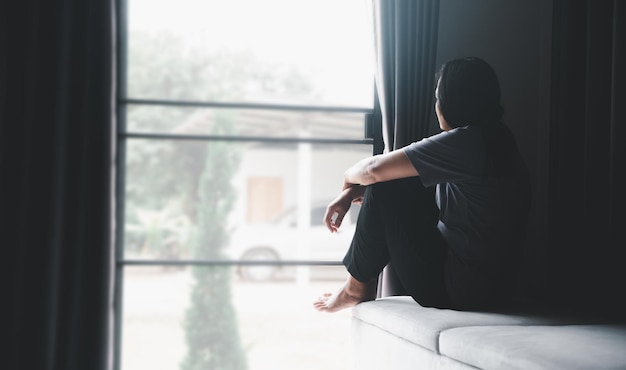 Schizophrenie mit einsamem und traurigem Depressionskonzept für psychische Gesundheit Depressive Frau, die zu Hause auf dem Sofa sitzt und sich in einem dunklen Raum elend fühlt Frauen sind depressiv, ängstlich und unglücklich