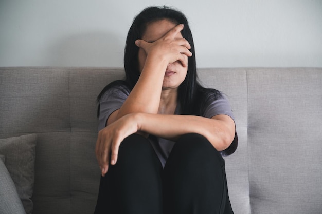 Schizophrenie mit einsamem und traurigem Depressionskonzept für psychische Gesundheit Depressive Frau, die zu Hause auf dem Sofa sitzt und sich in einem dunklen Raum elend fühlt Frauen sind depressiv, ängstlich und unglücklich