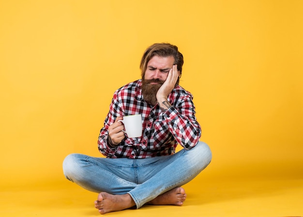 Schläfriger müder Kerl, er macht eine Kaffeepause Schöner reifer Kerl, der aus der Tasse trinkt Halten Sie eine Tasse Kaffee oder Tee Lifestyle-Konzept Schöner Hipster-Mann mit einer Tasse Kaffee