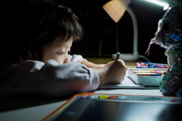 Schläfriger Student, der Hausaufgaben macht Asiatisches Kind ist müde