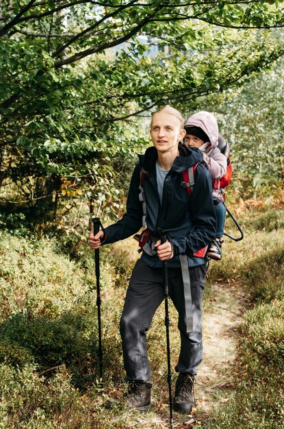 Schläfriges müdes Kind, das mit Vater im Rucksack draußen spaziert