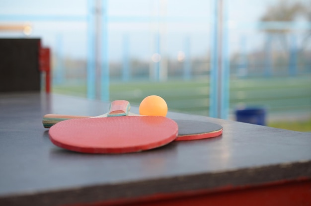 Schläger und Ball auf dem Ping-Pong-Tisch im Sporthof im Freien Aktives Sport- und körperliches Trainingskonzept