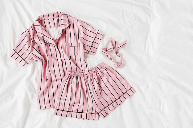 Schlafanzug für Pyjamas. Klassisches rosa Schlafkleid mit Streifen im Bett. Guten Morgen Konzept. Flache Lage, Ansicht von oben