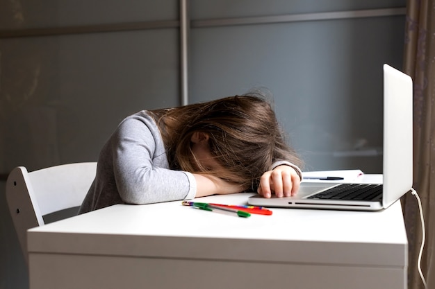 Schlafen am Schreibtisch beim Laptop-Mädchen sitzen