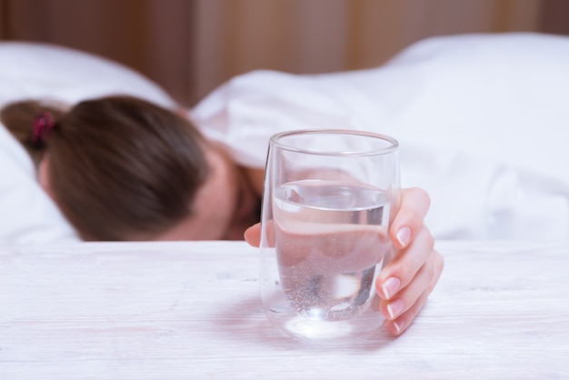Schlafende Frau, die Hand zum Glas Wasser übergibt