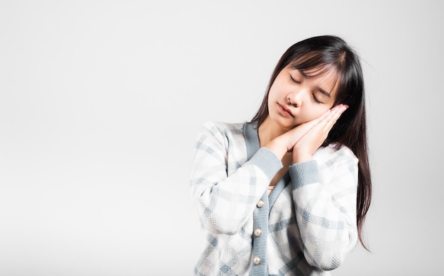 Schlafende Frau täuschte Gefühle schlafend müde Augen geschlossen träumend mit den Händen zusammen in der Nähe des Gesichts, Portrait asiatische schöne junge weibliche Schlafstudioaufnahme isoliert auf weißem Hintergrund mit Kopierraum