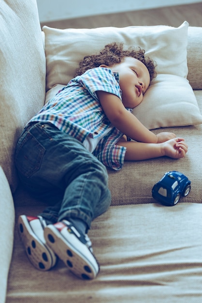 Foto schlafender kleiner junge. kleines afrikanisches baby, das schläft, während es zu hause auf der couch liegt