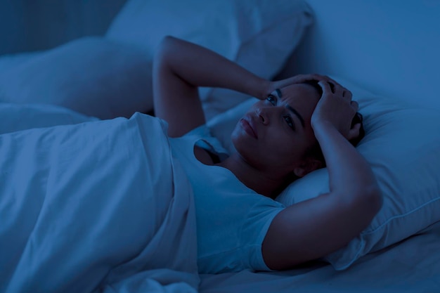 Schlafproblem gestresste afroamerikanische Frau, die im Bett liegt und den Kopf berührt
