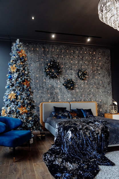 Schlafzimmer in dunklen Farben mit geschmücktem Weihnachtsbaum und Girlande