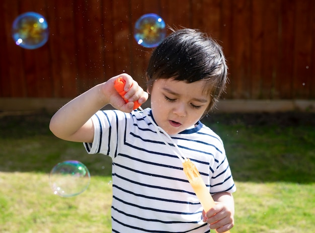 Schlagseifenblasen des glücklichen Jungen im Garten