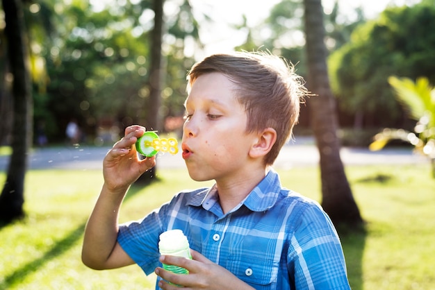 Schlagseifenblasen des Jungen im Park