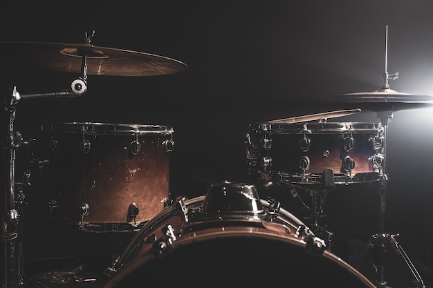 Foto schlagzeug, bassdrum, hi-hat, becken auf dunklem hintergrund mit strahlen aus einem scheinwerfer, kopierraum.