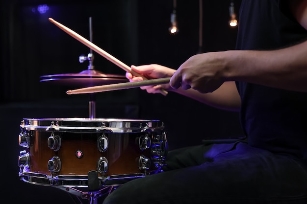 Schlagzeuger spielt Drumsticks auf einer Snaredrum im Dunkeln. Konzert- und Live-Performance-Konzept.