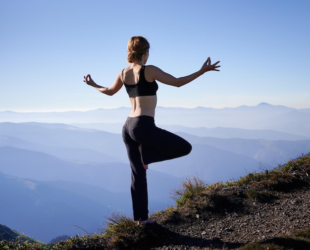 Schlanke Frau, die in Pose Yoga in der Natur steht