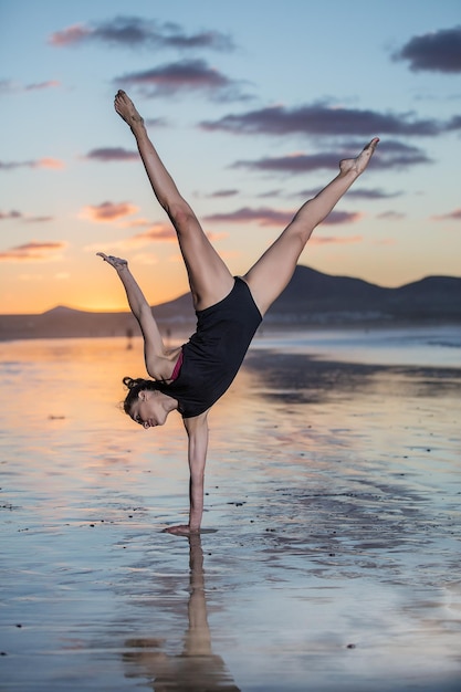 Schlanke Frau trainiert Yoga am Meer