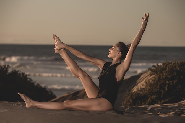 Schlanke Frau übt Yoga am Strand