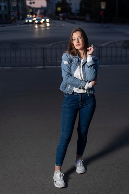 Schlanke junge Frau zu Fuß am Abend Stadtstraße Sommerzeit Junges stilvolles Mädchen auf Stadthintergrund Vertikaler Rahmen