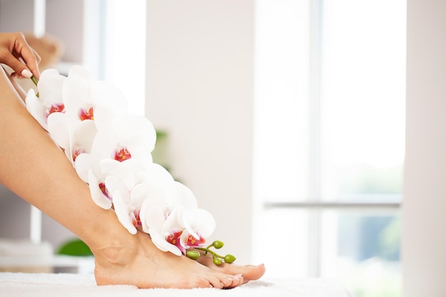 Schlanke lange Frauenbeine mit rosa Blumen