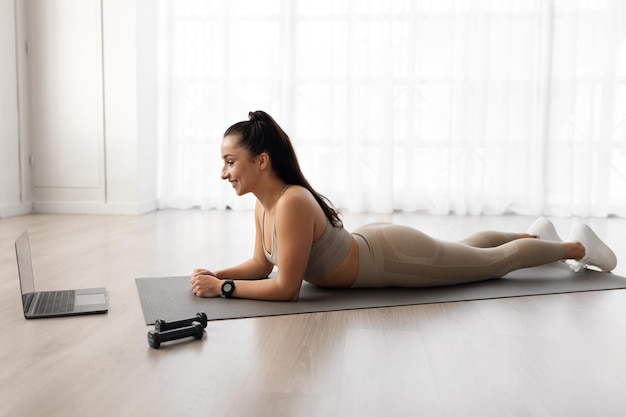 Schlanke sportliche junge Frau besucht Online-Fitness-Kurs