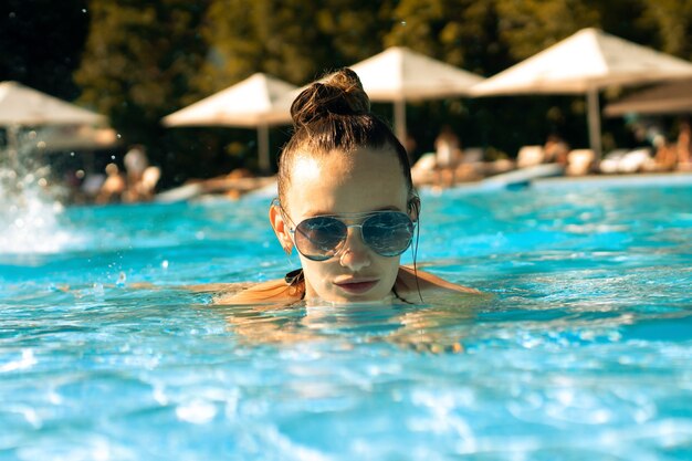 Schlankes Mädchen in der Sonnenbrille am Pool