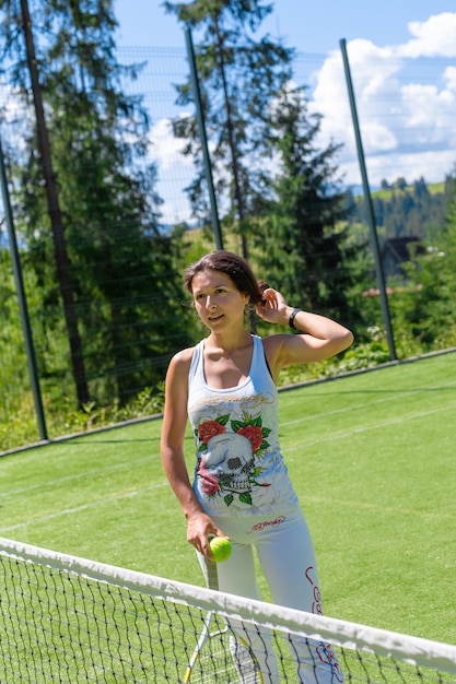 Schlankes wunderschönes Mädchen, das bereit ist, an einem hellen Sommertag auf dem Platz Tennis zu spielen.