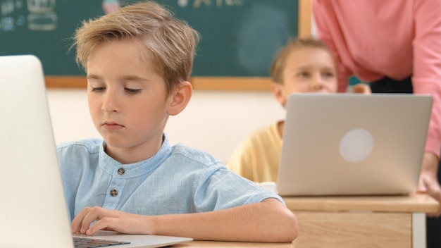 Schlauer Junge arbeitet an einem Laptop, während verschiedene Kinder Systempädagogik programmieren