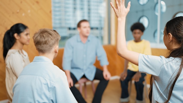 Foto schlaues mädchen hebt die hand, um fragen zu stellen, während der gruppentherapie.